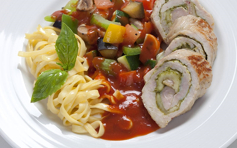 Gebratenes Röllchen von der Putenbrust mit Basilikum und Mozzarella gefüllt, auf feiner Ratatouille und Tagliatelle